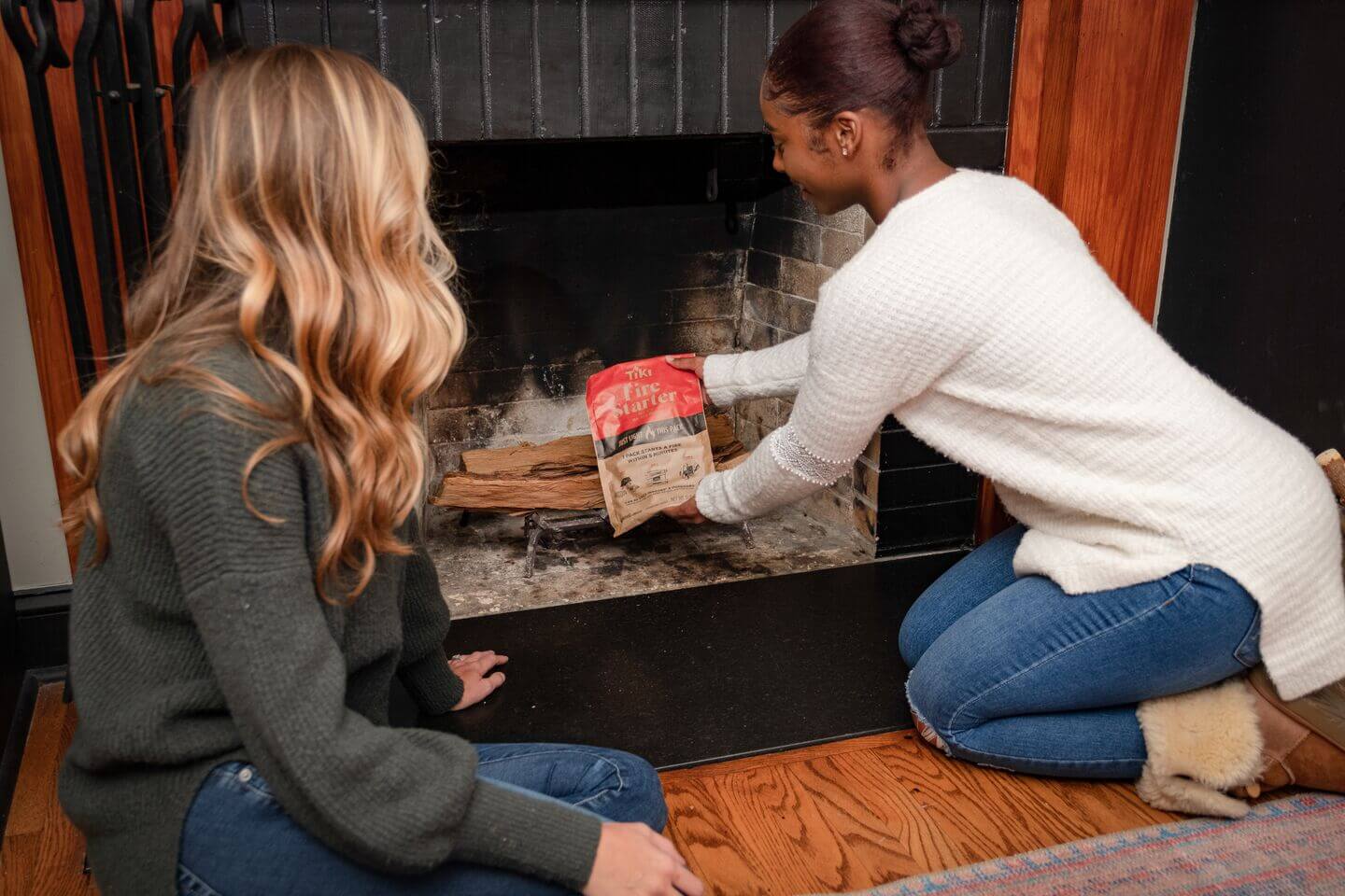 two women starting a fire in an indoor fireplace with the tiki brand fire starter