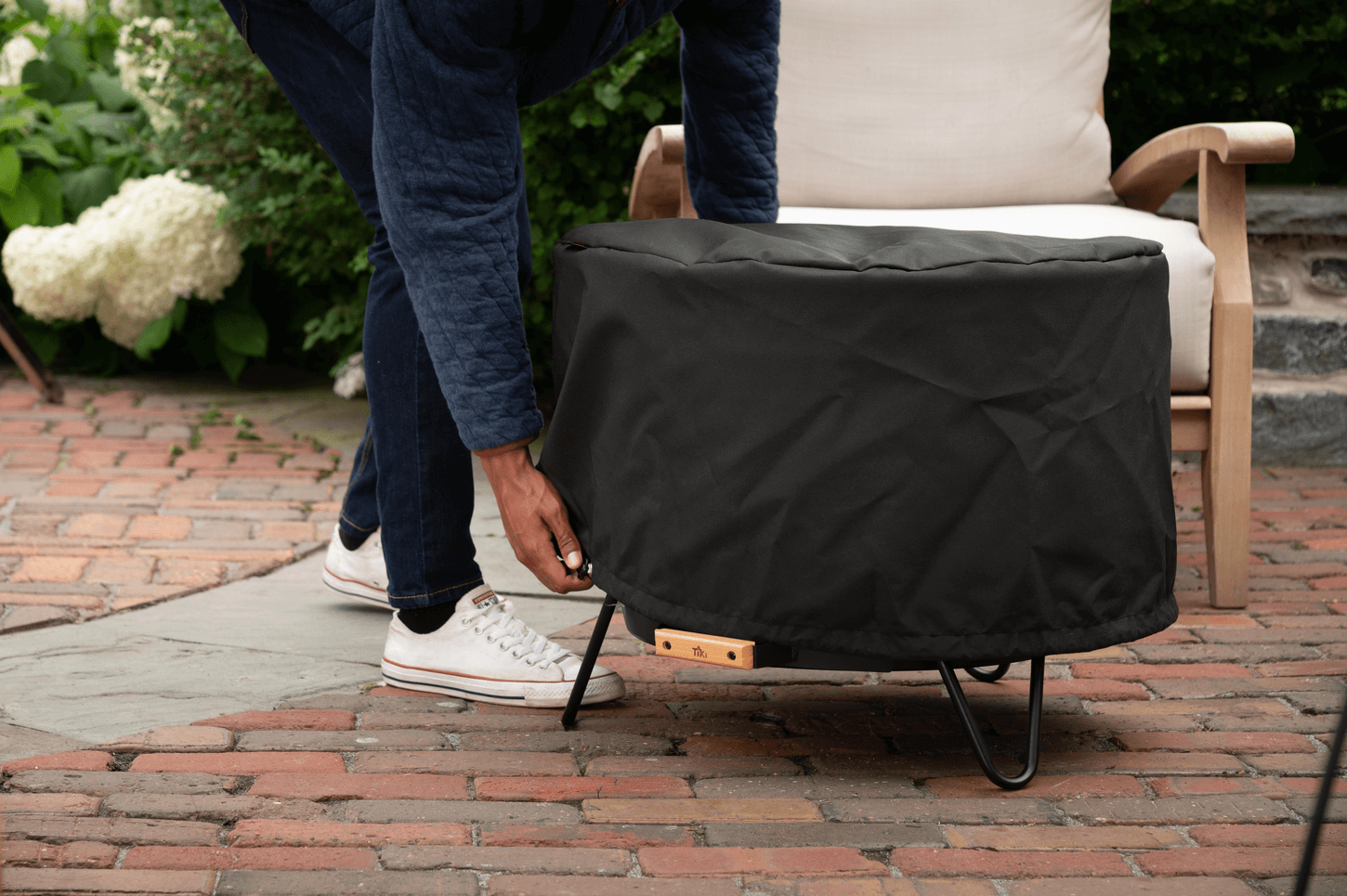 Man placing fire pit cover on top of patio smokeless fire pit