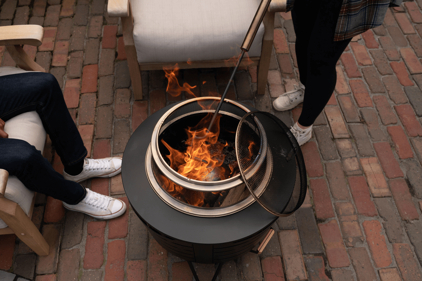 Aerial view of patio smokeless fire pit with Screen and Poker and woman stoking the fire