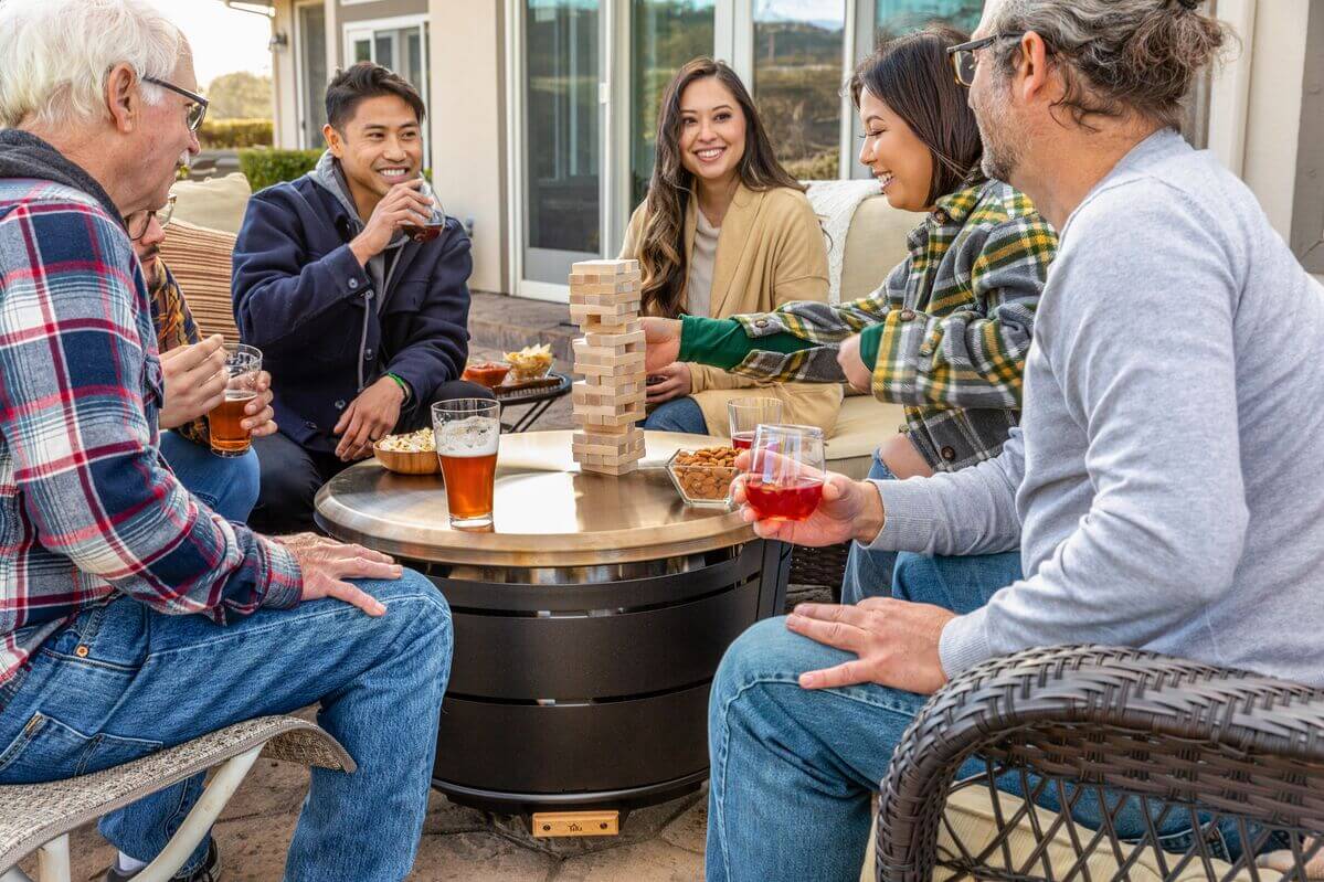 friends surrounding reunion smokeless fire pit with tabletop cover on and playing jenga on tabletop