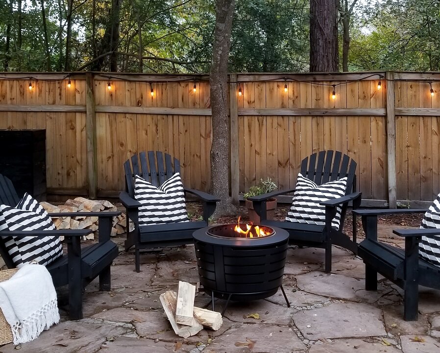 Black adirondack chairs with black and white striped pillows around a smokeless fire pit