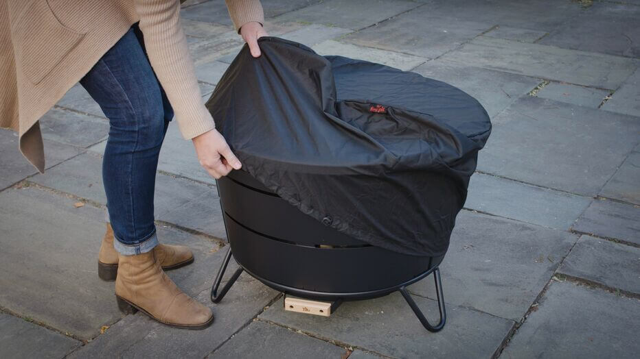 Woman putting a cloth cover over reunion smokeless fire pit