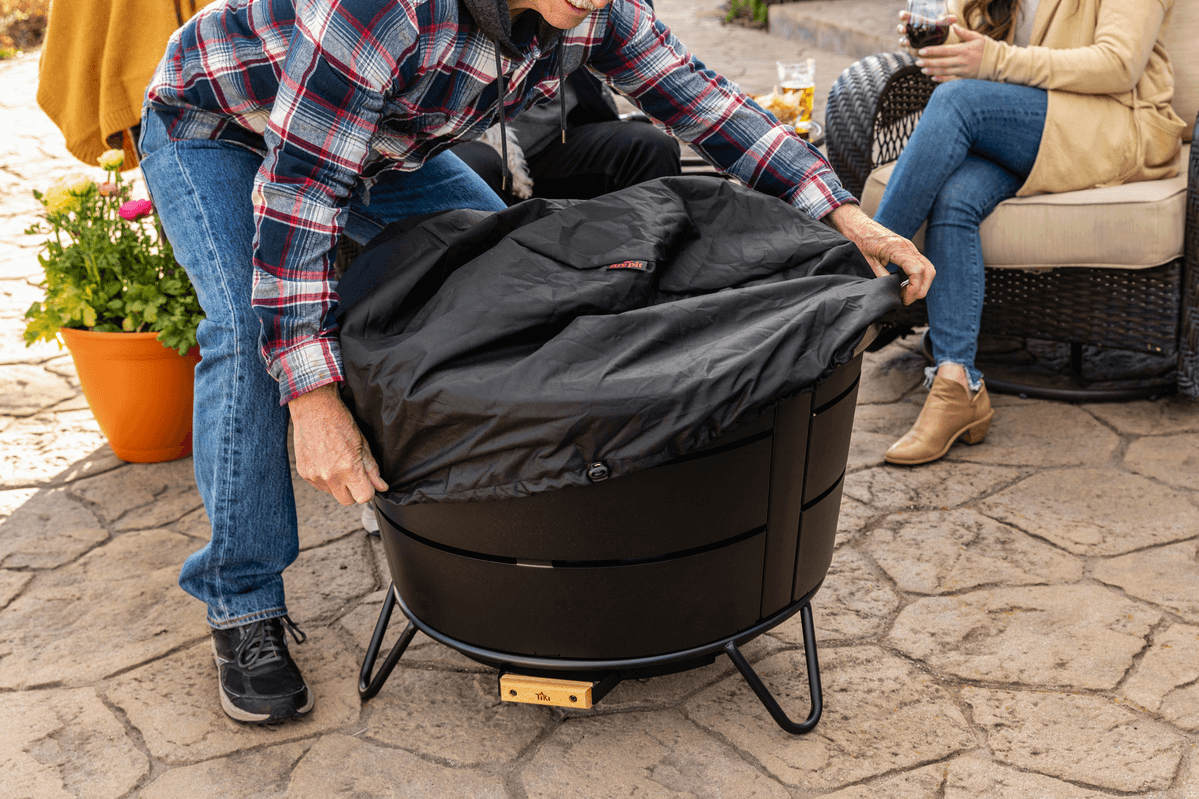 Man putting on a cover on a smokeless fire pit for storage