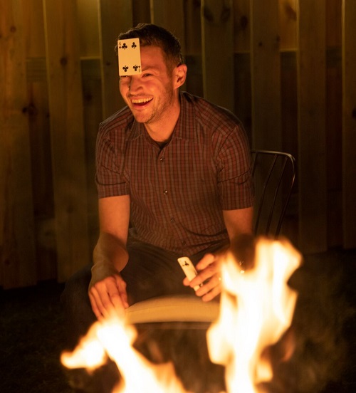 laughing while playing cards around a fire